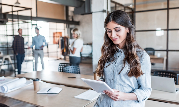 Smiling young businesswoman using digital tablet in office.